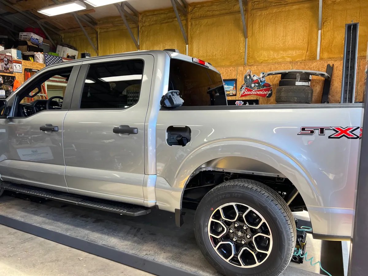 A silver pickup truck on a lift inside McElroy Auto Repair