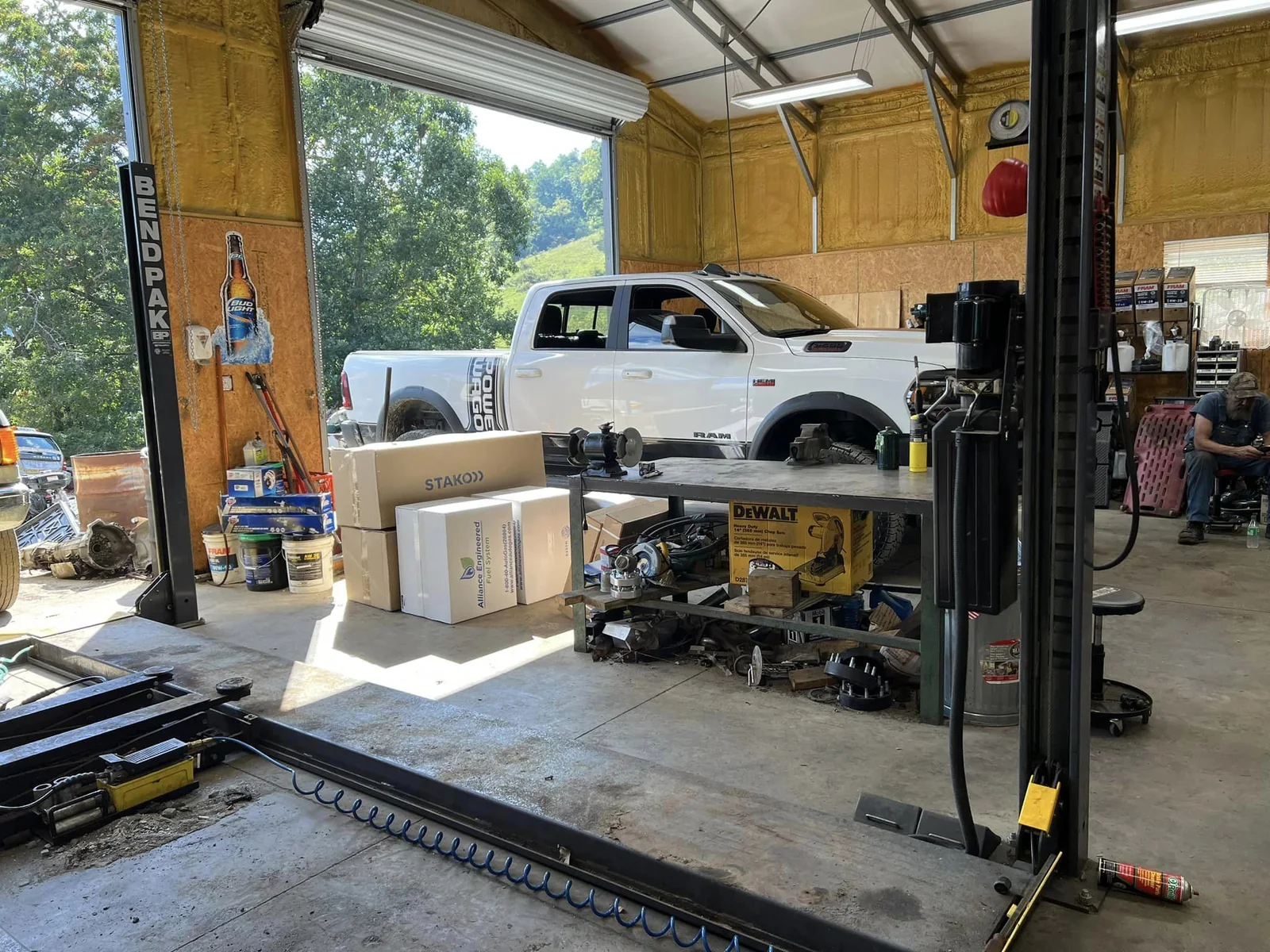 A white Ram Power Wagon inside McElroy Auto Repair's working bay between two vehicle lifts